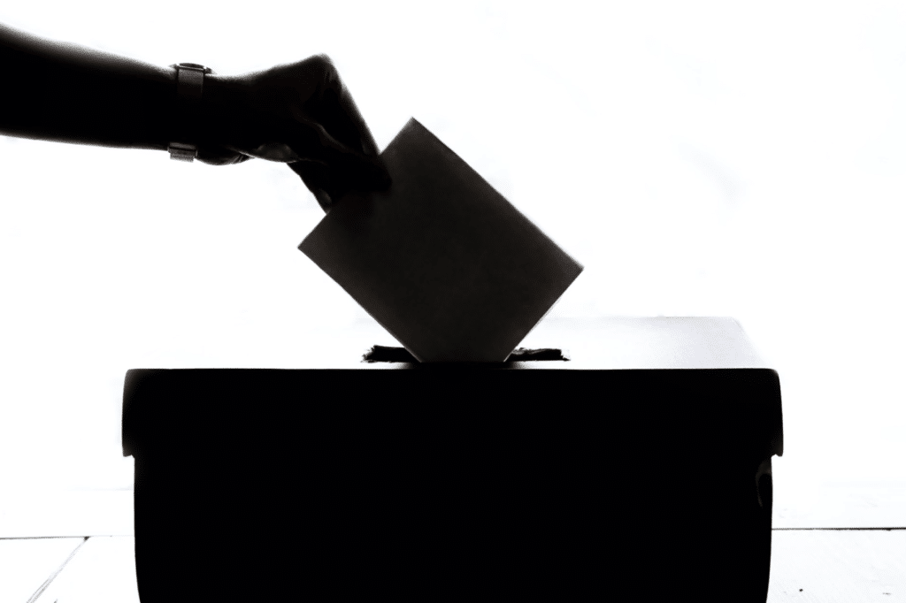 A woman's hand drops a ballot paper into a box