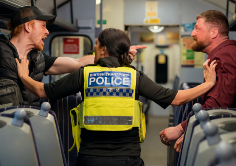 A British Transport Police officer breaks up an altercation in a train carriage.